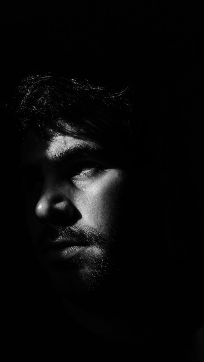 High-contrast black and white portrait of a man with hard shadows