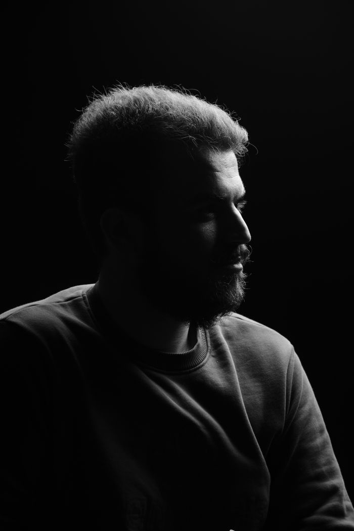 Bearded man in profile against black, a single rim light on his face