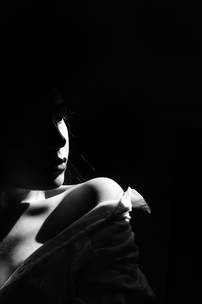 Woman in low light, bare shoulder and hair picked out by a soft key light
