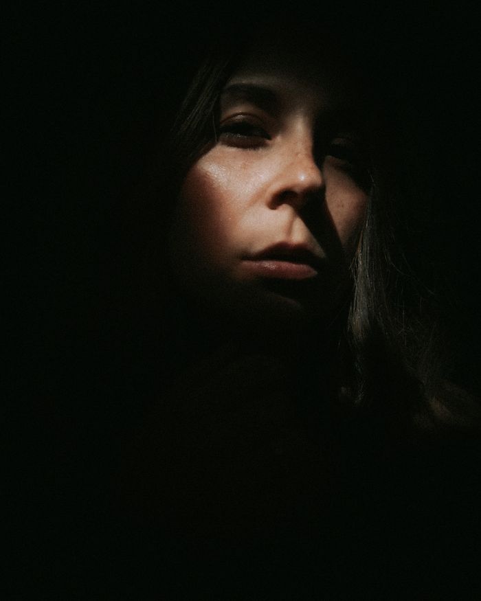 Woman looking straight at the camera, her face half covered by shadow
