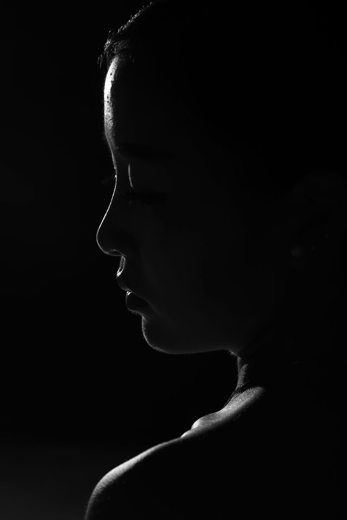 Silhouetted profile of a woman with only the edge of her face lit