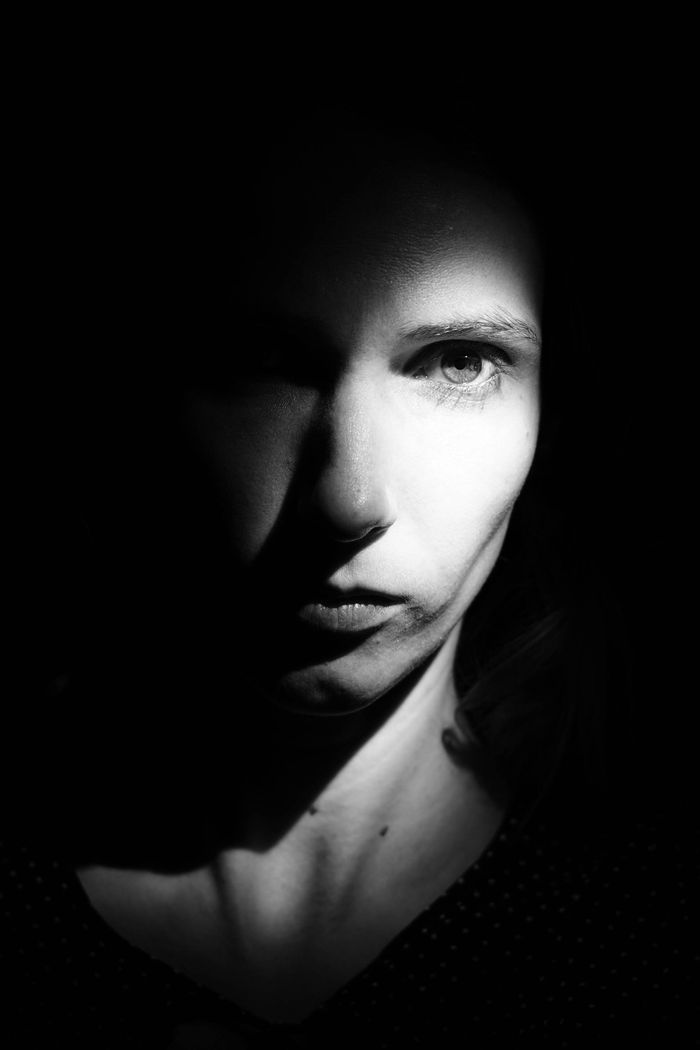 Woman's face lit from one side, the other half falling into shadow